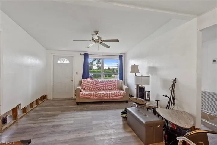 Living room with vaulted ceiling, light wood-type flooring, and ceiling fan