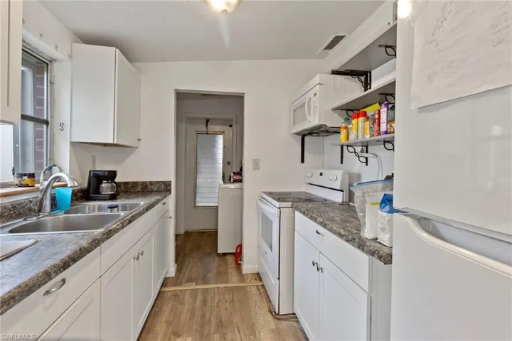 Kitchen with white appliances, white cabinetry, and sink
