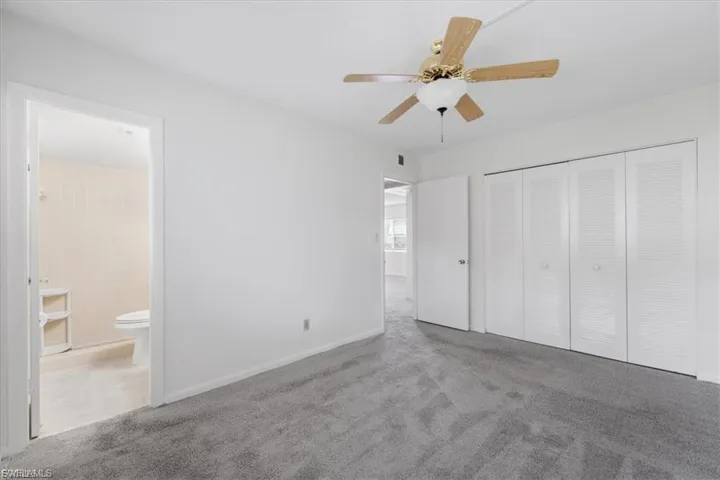 Unfurnished bedroom featuring carpet floors, a ceiling fan, a closet, and connected bathroom