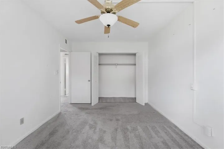 Unfurnished bedroom with carpet, a ceiling fan, and a closet