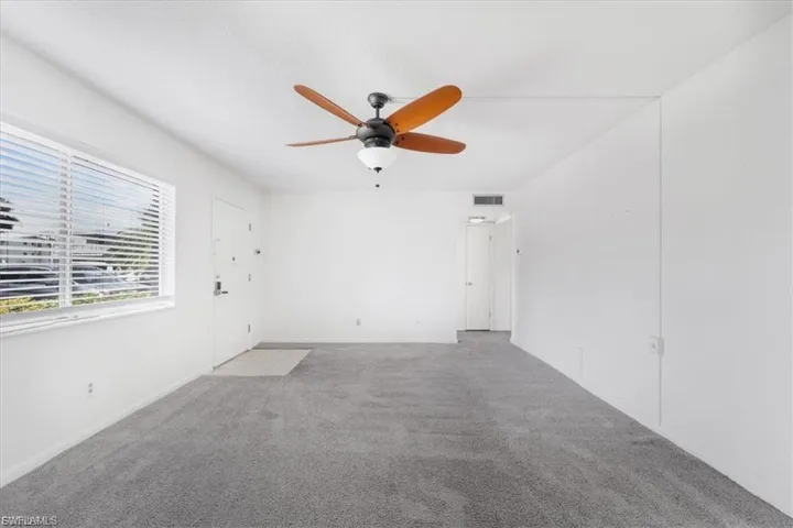 Carpeted spare room featuring a ceiling fan