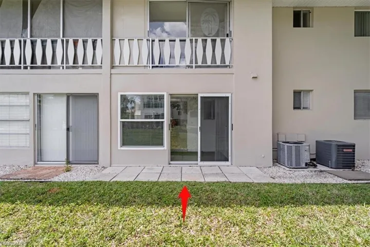 Rear view of house with a lawn, stucco siding, a patio area, and a balcony