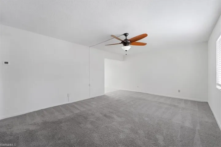 Carpeted empty room with ceiling fan and a textured ceiling