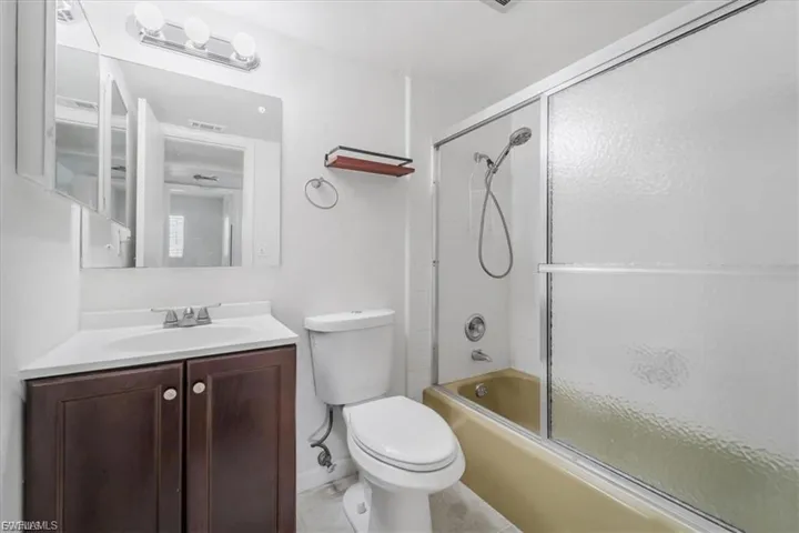 Full bath featuring combined bath / shower with glass door and vanity