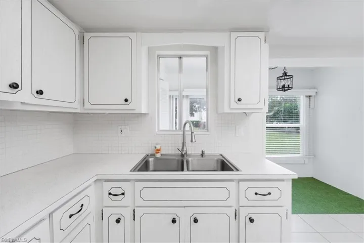 Kitchen with plenty of natural light, light countertops, backsplash, and white cabinetry