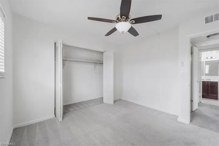 Unfurnished bedroom with light colored carpet, a ceiling fan, and a closet