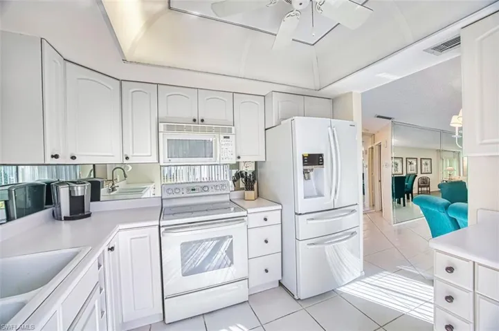Kitchen with white appliances, white cabinets, and light tile patterned floors