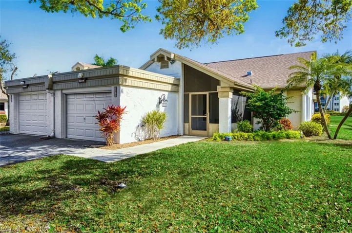 View of front of house featuring a front lawn, driveway, stucco siding, and an attached garage