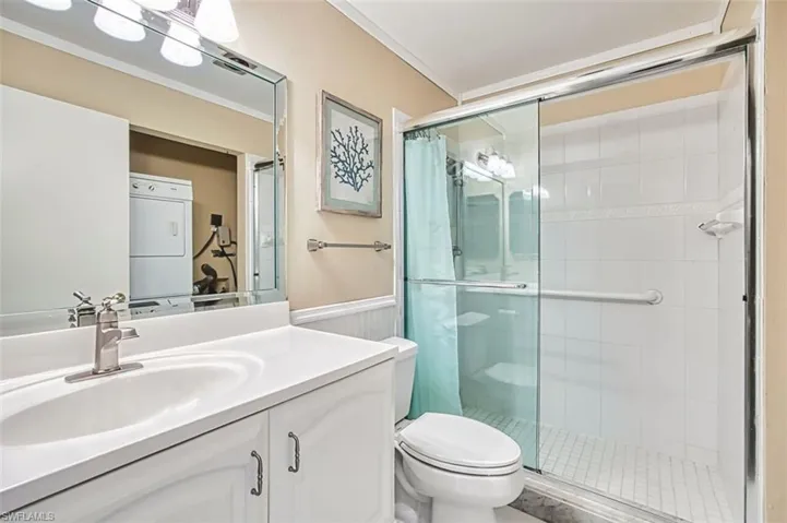 Full bath featuring vanity, a shower stall, crown molding, and wainscoting