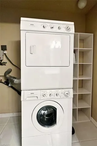 Laundry room featuring light tile patterned flooring and stacked washer and dryer