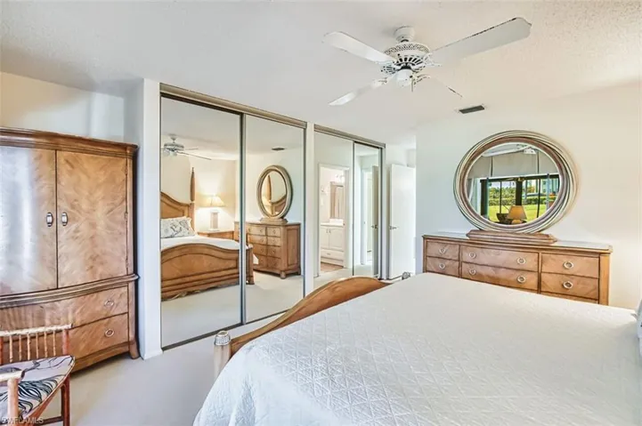 Bedroom featuring carpet floors, ceiling fan, multiple closets, and a textured ceiling