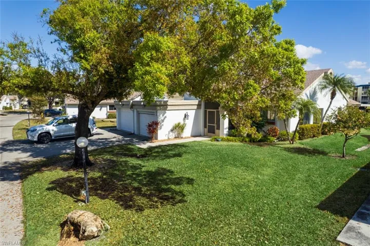 View of front of property with driveway, stucco siding, a residential view, and a front lawn