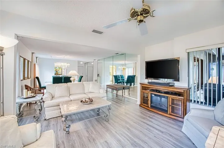Living room with suspended lighting, wood finished floors, a ceiling fan, and a textured ceiling