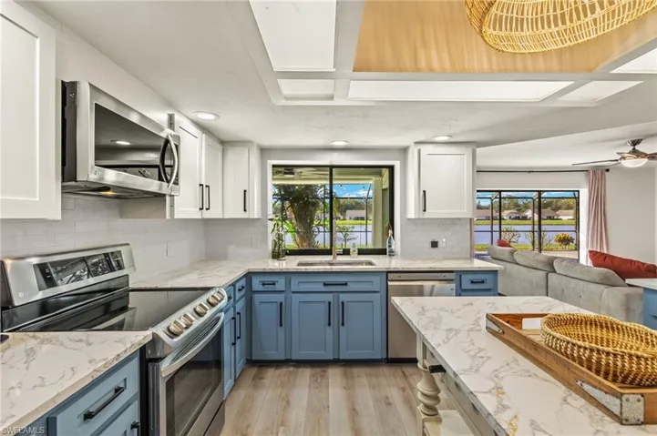 Kitchen with appliances with stainless steel finishes, blue cabinetry, plenty of natural light, and light hardwood / wood-style floors
