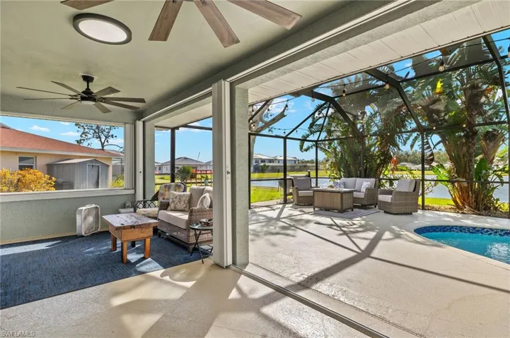 View of patio featuring a water view, ceiling fan, a lanai, and an outdoor living space