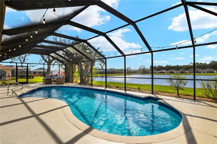 View of pool with a patio area, a lanai, and a water view