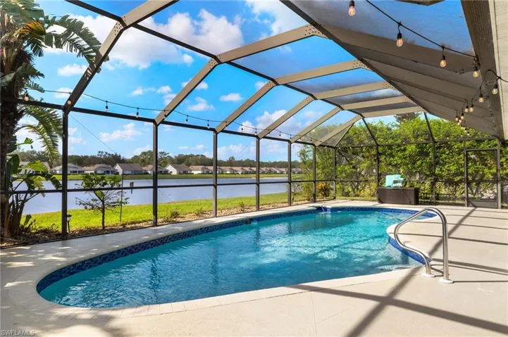 View of pool featuring a water view, a patio, and glass enclosure