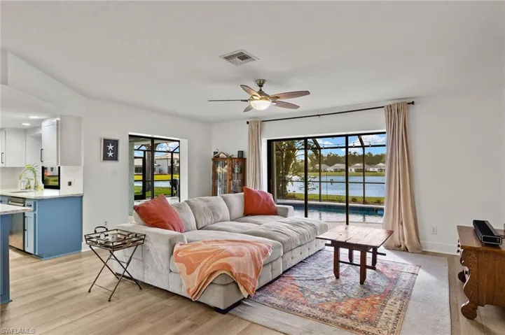 Living room with a water view, light hardwood / wood-style floors, sink, and ceiling fan