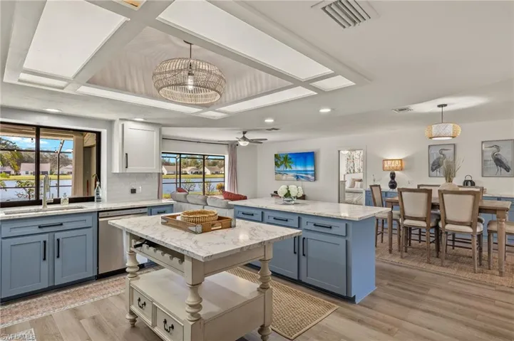 Kitchen with light hardwood / wood-style flooring, hanging light fixtures, sink, a center island, and stainless steel dishwasher