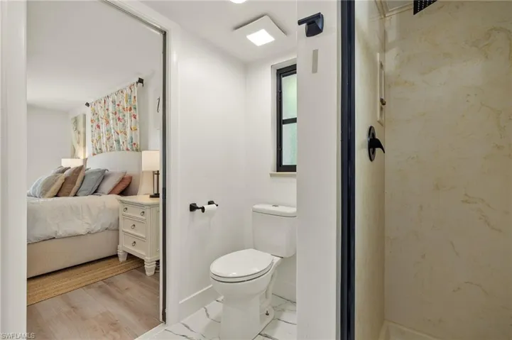 Bathroom with toilet, walk in shower, and wood-type flooring