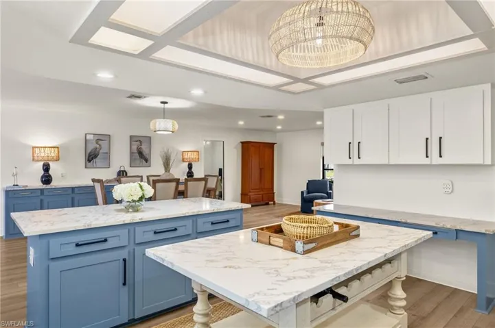 Kitchen with blue cabinetry, a center island, light wood-type flooring, and pendant lighting