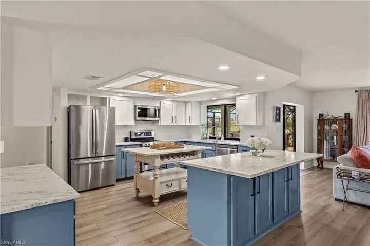 Kitchen with a kitchen island, white cabinets, light hardwood / wood-style flooring, and stainless steel appliances