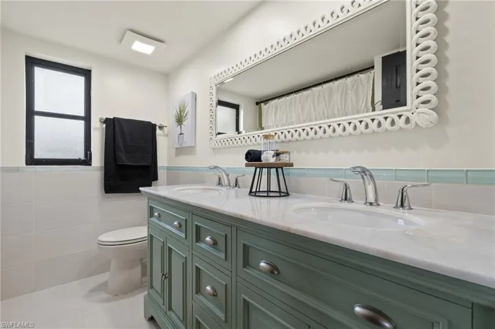 Bathroom with tile walls, toilet, vanity, curtained shower, and tile patterned flooring