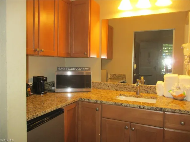 Kitchen featuring stainless steel refrigerator, light stone counters, and maple cabinets