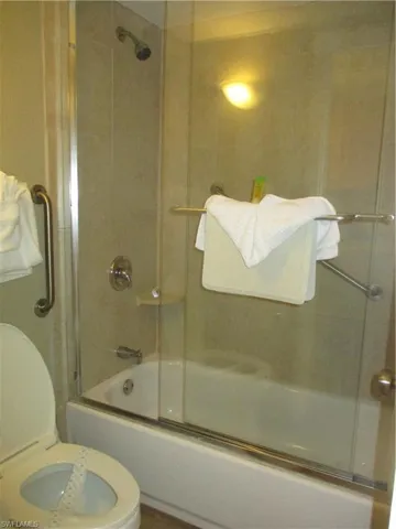 Full bath with bath / shower combo with glass door and handrails