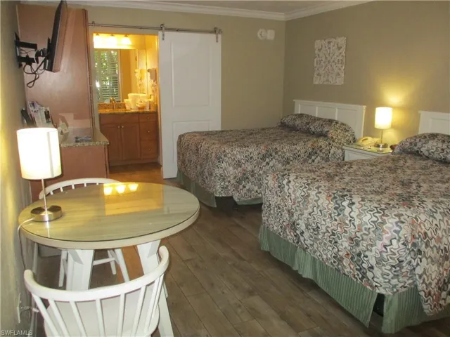 Room featuring a barn door, crown molding, wood tile floors, and ensuite bath