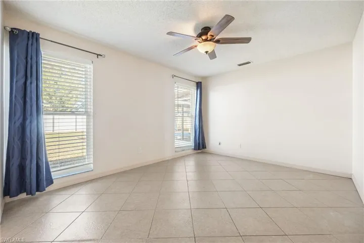 Master bedroom featuring a textured ceiling, light tile patterned floors, and ceiling fan