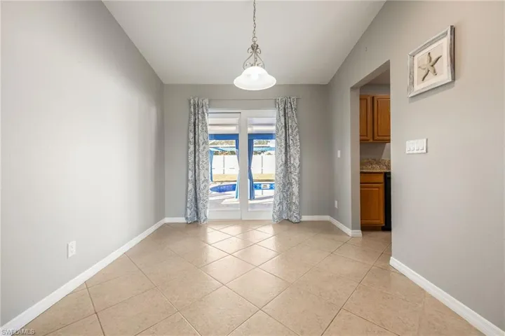 Unfurnished dining area with light tile patterned floors and lofted ceiling