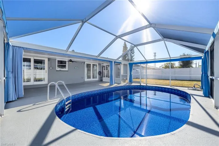 View of swimming pool featuring a sunroom, french doors, a patio, and glass enclosure