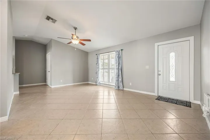 Entryway featuring ceiling fan, light tile patterned floors, and vaulted ceiling