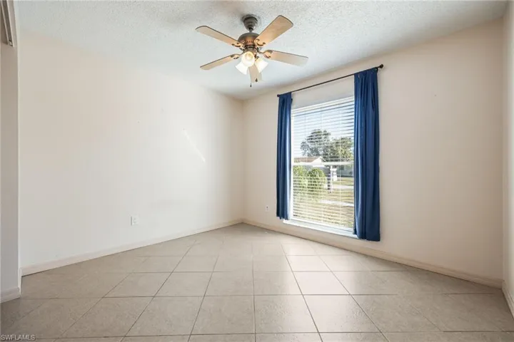 Spare room featuring a textured ceiling, ceiling fan, and light tile patterned floors