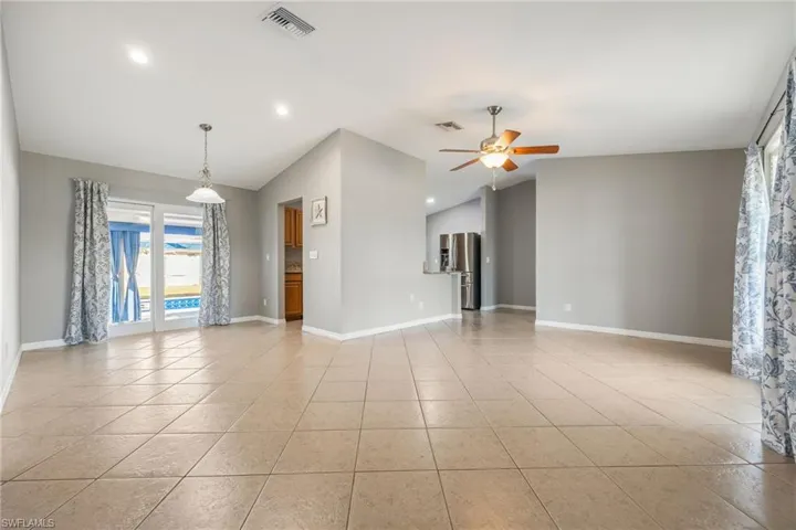 Unfurnished room featuring vaulted ceiling, light tile patterned floors, ceiling fan, and recessed lighting