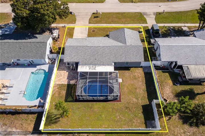 Aerial view of property and surrounding area featuring property parcel outlined and a pool area