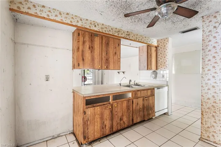 Kitchen featuring light countertops, white dishwasher, a textured ceiling, ceiling fan, and light tile patterned flooring