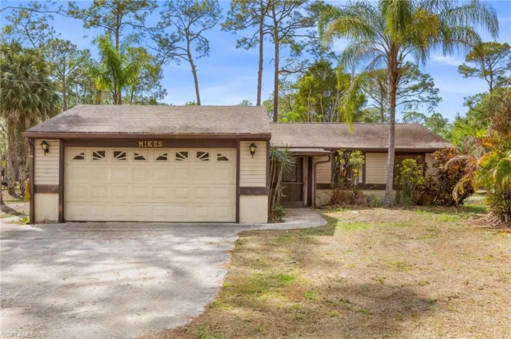 Ranch-style home with driveway, a shingled roof, a front lawn, and an attached garage