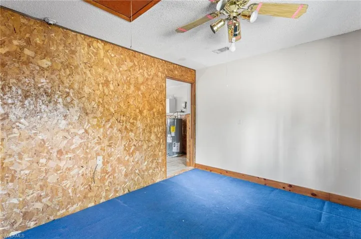 Spare room with a textured ceiling, a ceiling fan, electric water heater, and carpet flooring