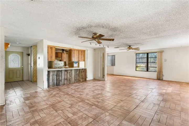 Unfurnished living room featuring a textured ceiling and ceiling fan