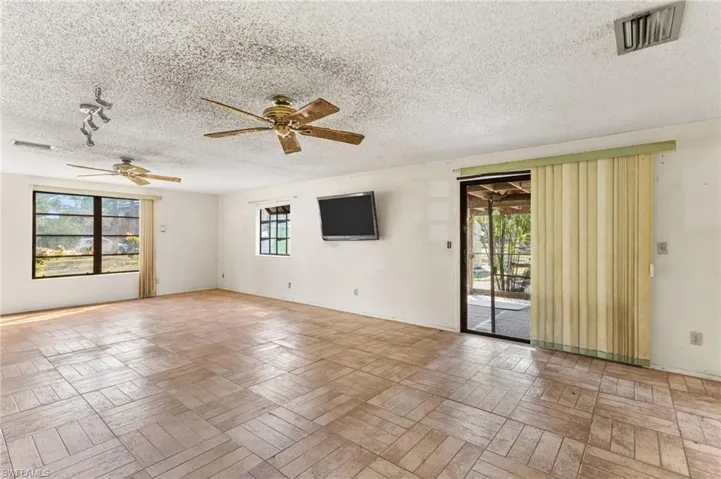 Empty room with plenty of natural light, a ceiling fan, and a textured ceiling