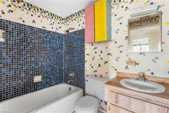 Full bath with wallpapered walls, vanity, and  shower combination