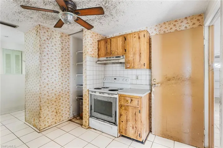 Kitchen with white electric range oven, a textured ceiling, light countertops, a ceiling fan, and light tile patterned flooring