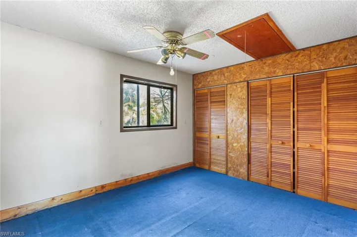 Unfurnished bedroom featuring two closets, a textured ceiling, a ceiling fan, and carpet floors