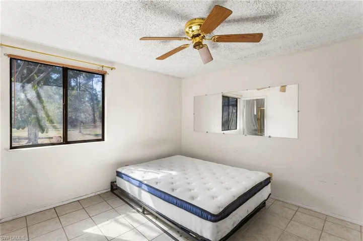 Bedroom featuring a textured ceiling, a ceiling fan, and light tile patterned flooring