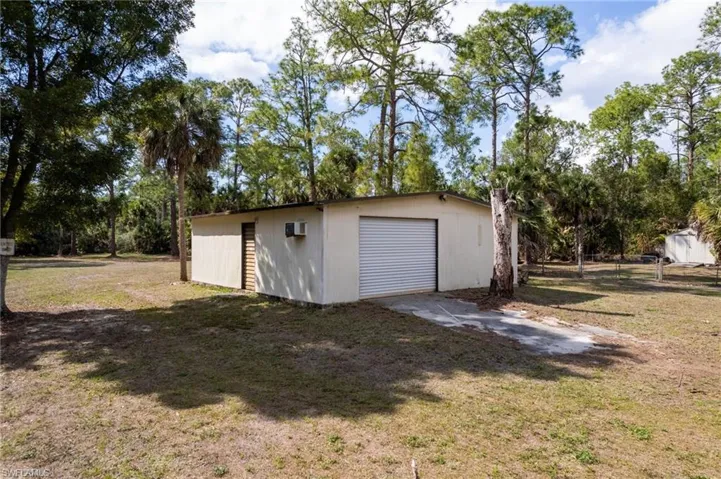 Detached garage featuring view of wooded area