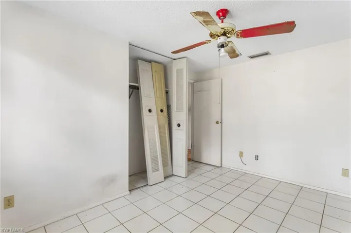 Unfurnished bedroom featuring a ceiling fan, a textured ceiling, a closet, and light tile patterned floors
