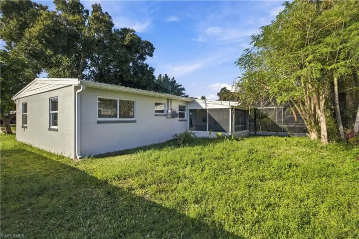 Single-story exterior featuring a light-toned smooth finish, sliding windows, and a screened-in enclosure