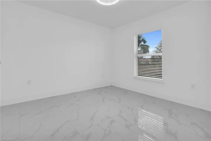 Unfurnished room featuring light marble finish flooring and baseboards